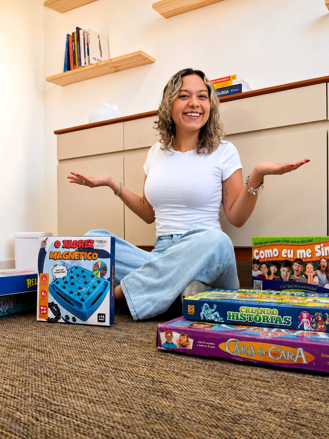 Larissa Benites sorrindo no consultório, com jogos e materiais de psicoterapia